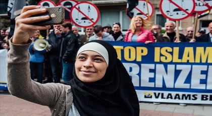 بالصور.. فتاة محجبة تتحدى مظاهرة ضد الإسلام بـ”السيلفي” في بلجيكا‎
